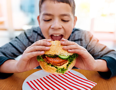 Buy stock photo Boy, home and eating burger for lunch, nutrition and delicious fast food for childhood development. Hungry, male person with yummy carb meal, healthy condiments and bite for wellness and growth