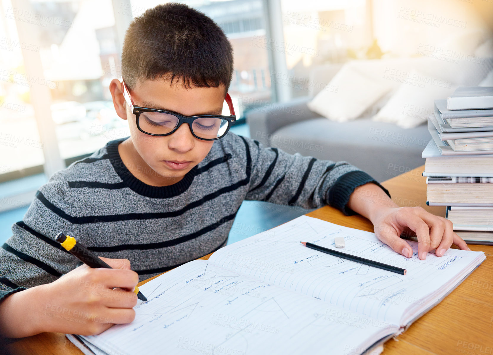Buy stock photo Boy child, student and writing in book for studying, education and learning homework on table at home. Smart little kid busy with mathematics, textbooks and problem solving for study in living room