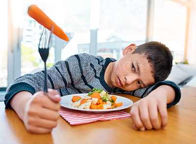 Buy stock photo Shot of an unhappy young boy refusing to eat his vegetables at home