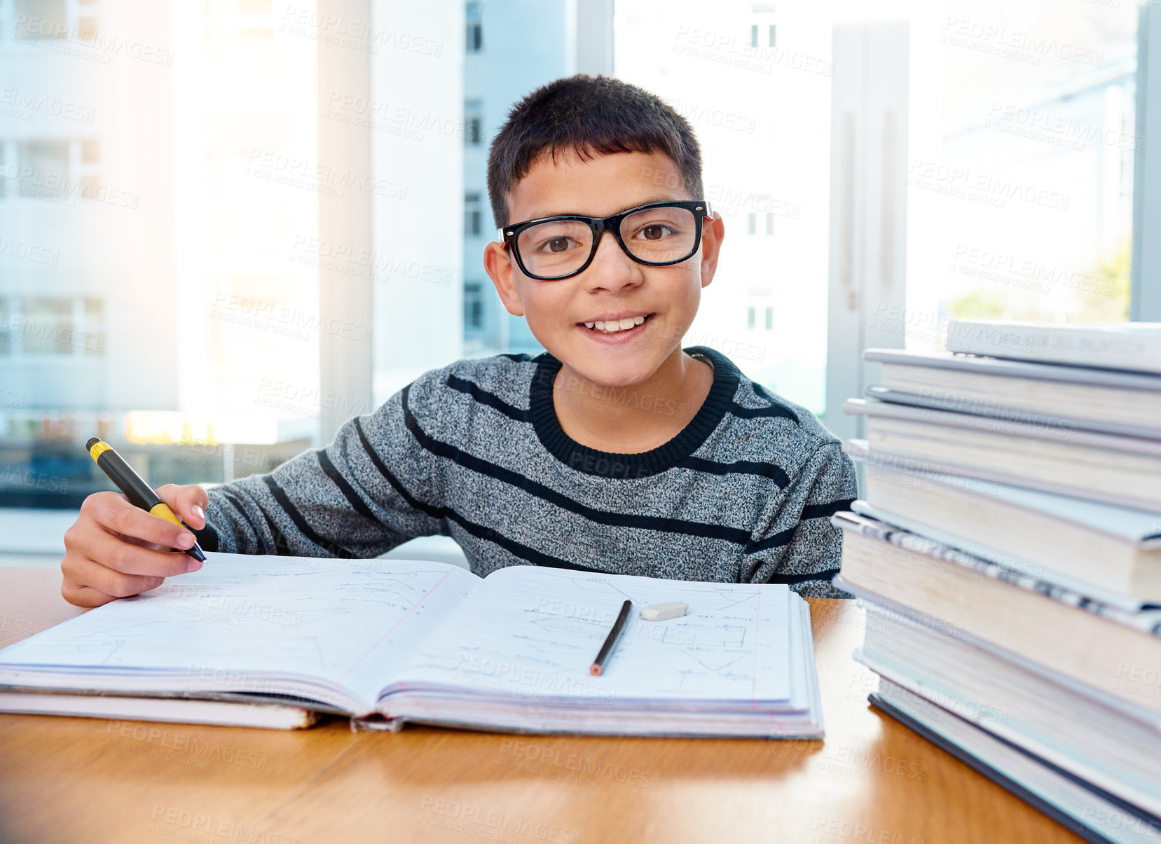 Buy stock photo Portrait of a determined young boy doing his homework at home