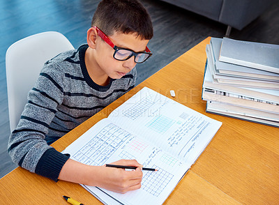 Buy stock photo Boy, student and writing in book for math, studying or homework for learning, assessment or education on table. Smart kid, young child and busy reading mathematics textbook, problem solving and focus