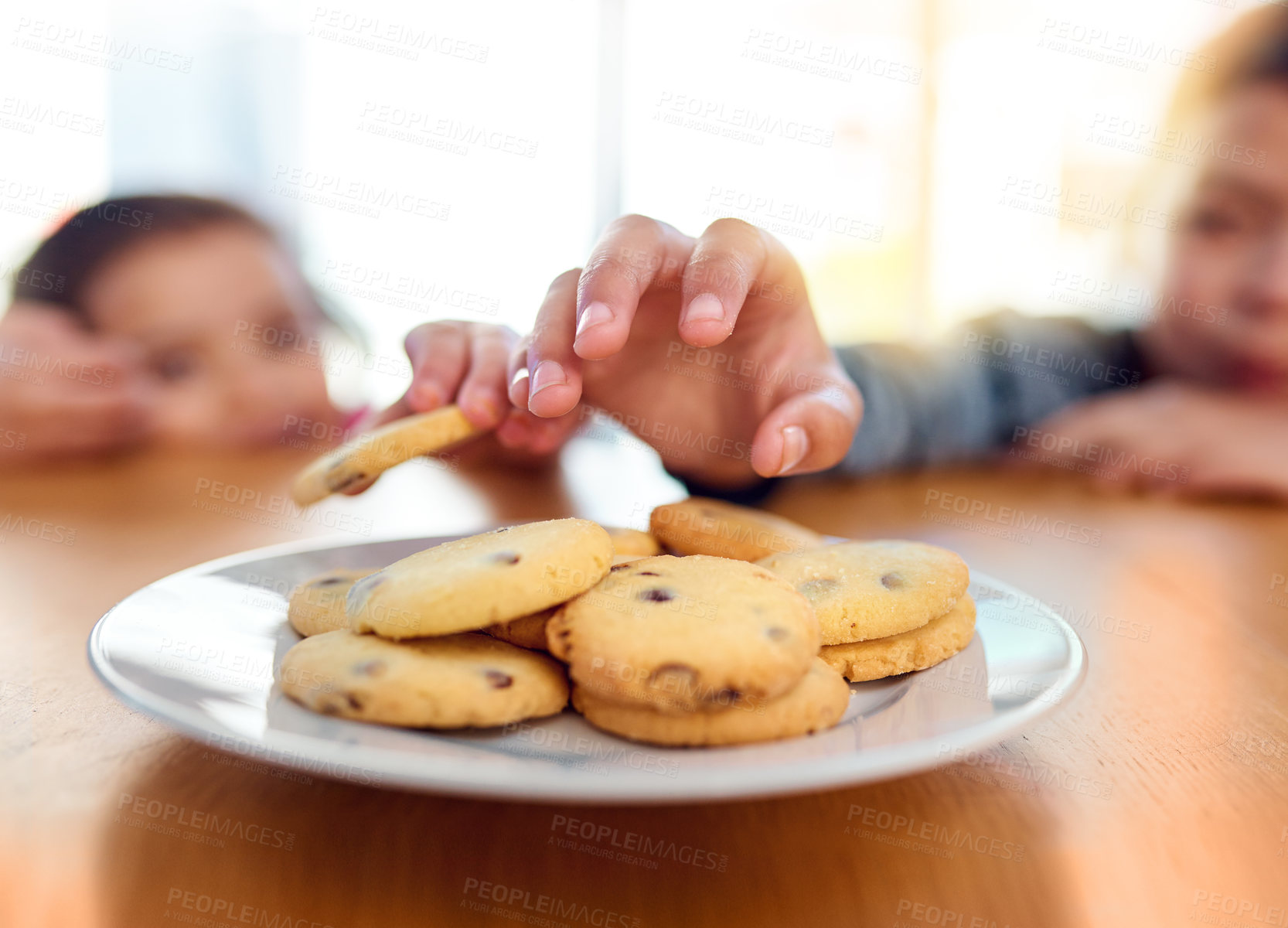 Buy stock photo Closeup shot of two mischievous young children stealing cookies on the kitchen table at home