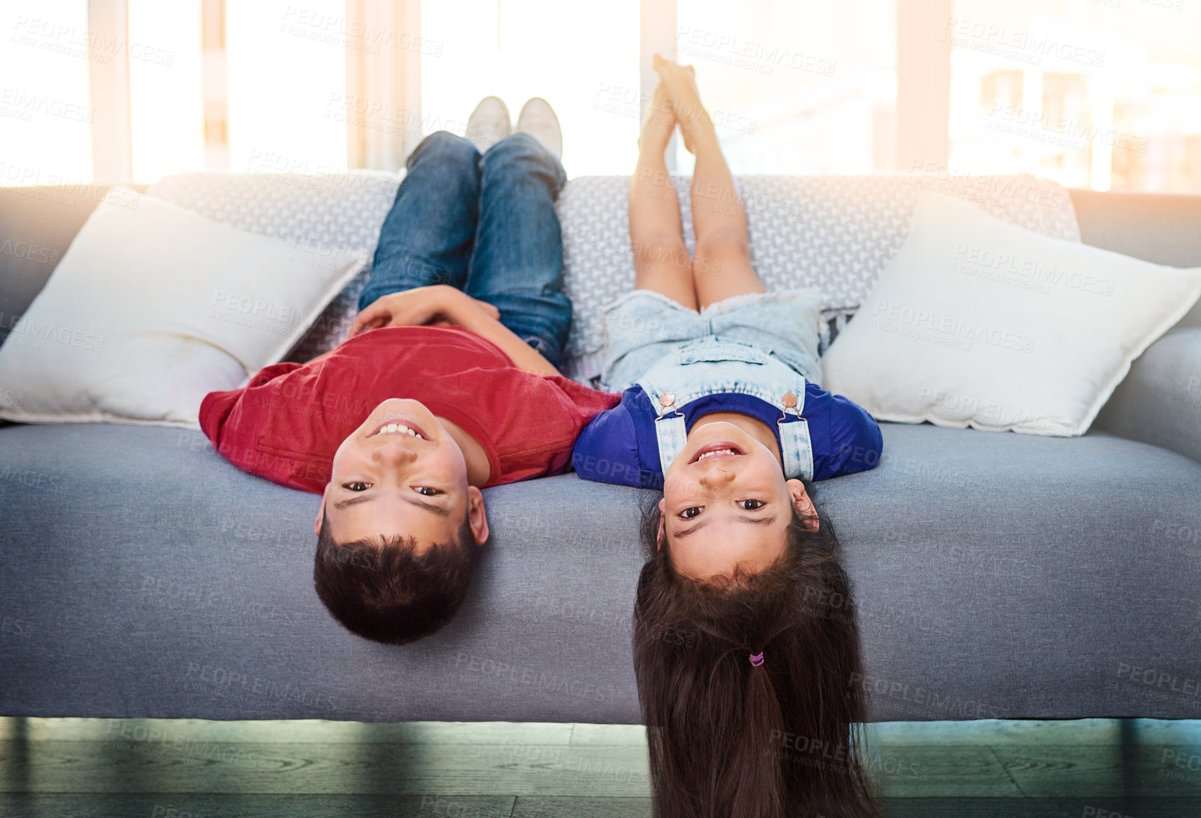 Buy stock photo Portrait of two young children lying upside down on a couch at home