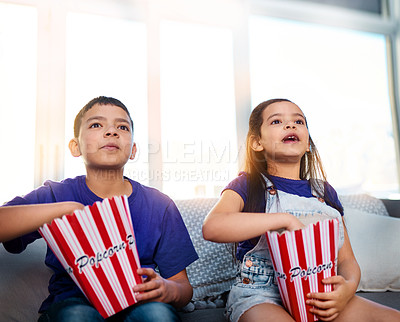 Buy stock photo Children, popcorn and watching on home sofa for movie entertainment as siblings, subscription or eating. Boy, girl and couch in apartment with snacks together in living room, streaming or television
