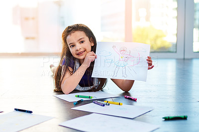 Buy stock photo Portrait of an adorable little girl lying down on the floor and showing her artwork at home