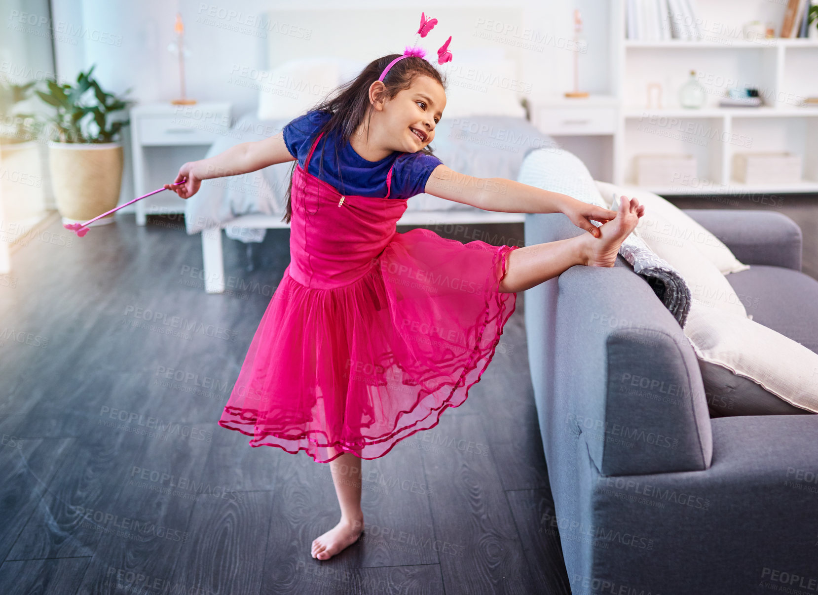 Buy stock photo Shot of an adorable little girl dressed up as a fairy showing off her ballet moves at home