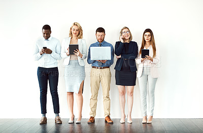 Buy stock photo Shot of a group of work colleagues standing in a line while using their wireless devices against a white background