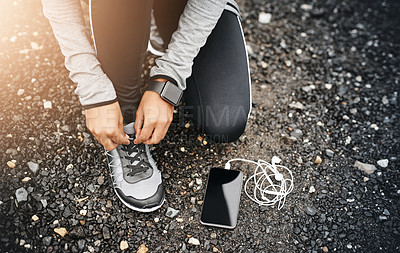 Buy stock photo Closeup shot of a sporty woman tying her shoelaces while exercising outdoors
