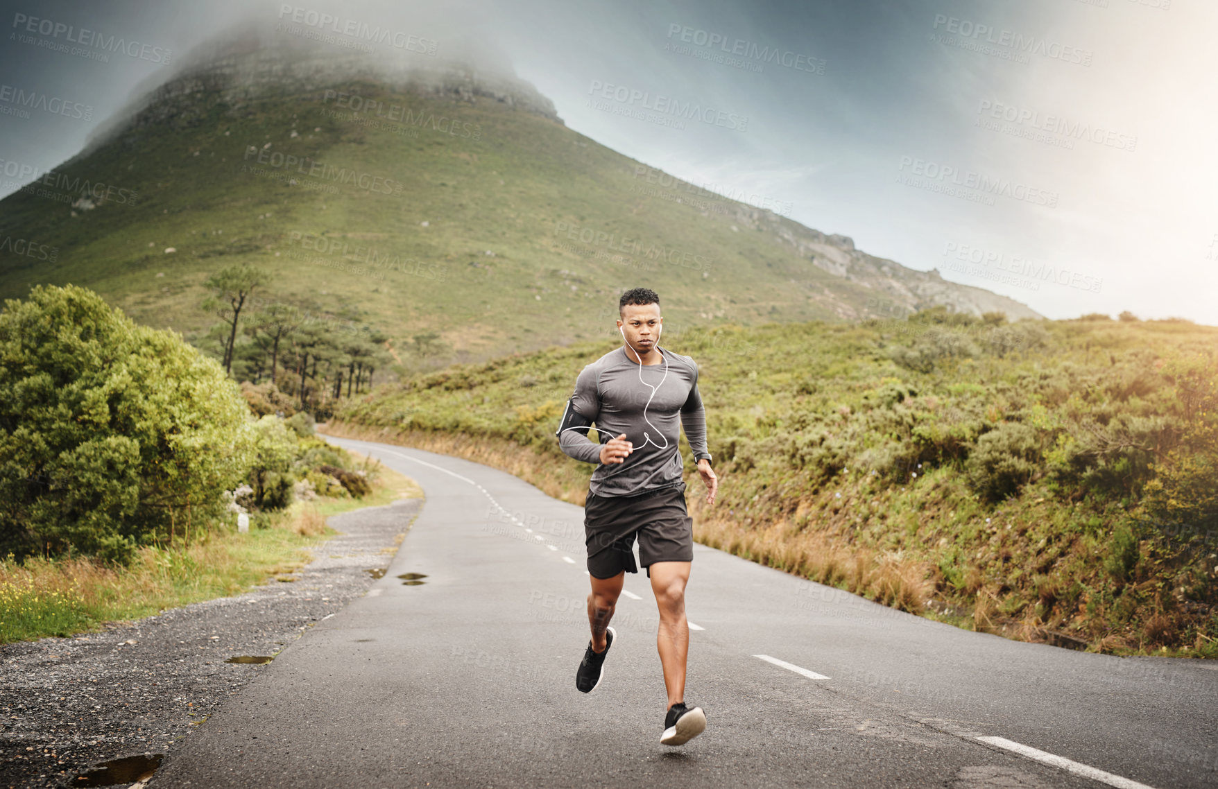Buy stock photo Man, running and training in nature in street for exercise, wellness and music with commitment for health. African male runner, listening and audio for focus, mindset and outdoor with workout on road