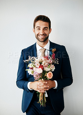 Buy stock photo Studio shot of a handsome young groom holding a bunch of flowers a gray background