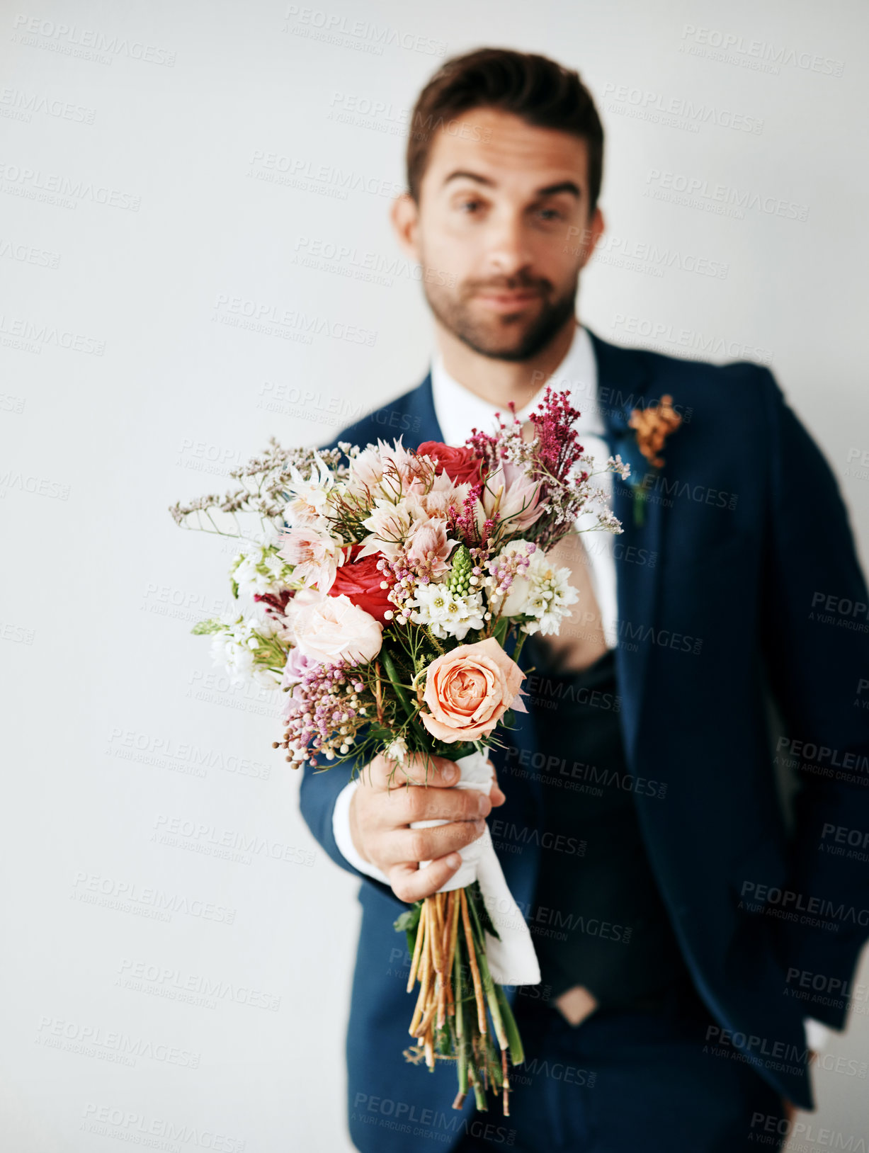Buy stock photo Studio shot of a handsome young groom holding a bunch of flowers a gray background