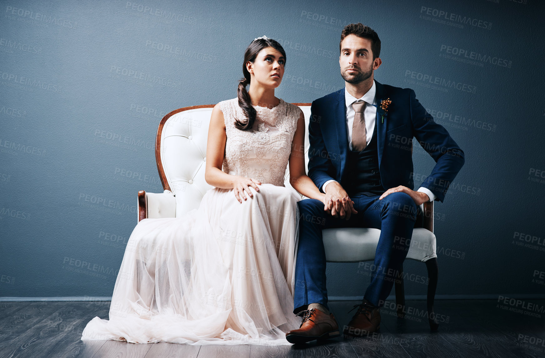 Buy stock photo Bride, groom or together in studio on chair for marriage, stress or concerned for wedding. People, couple or blue background with hand holding for commitment with fear, anxiety or mistake in Chicago