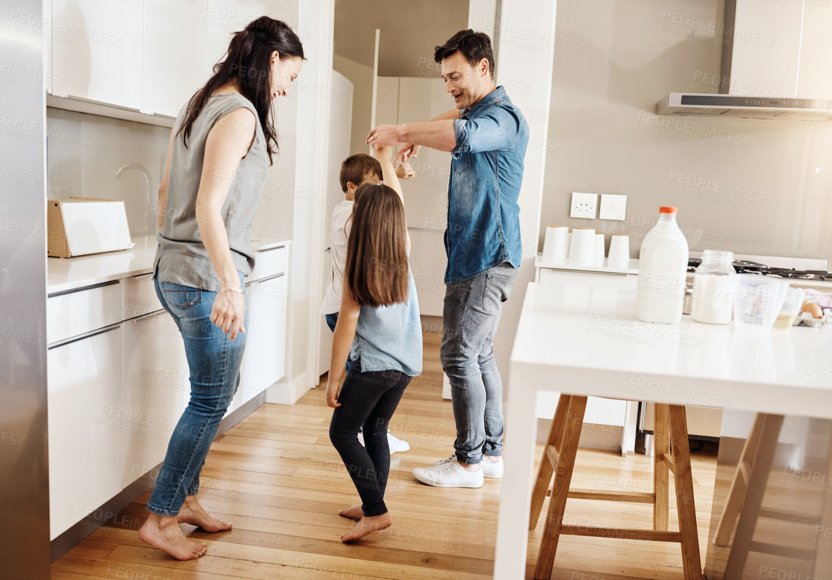 Buy stock photo Shot of a happy family of four dancing together in the kitchen at home