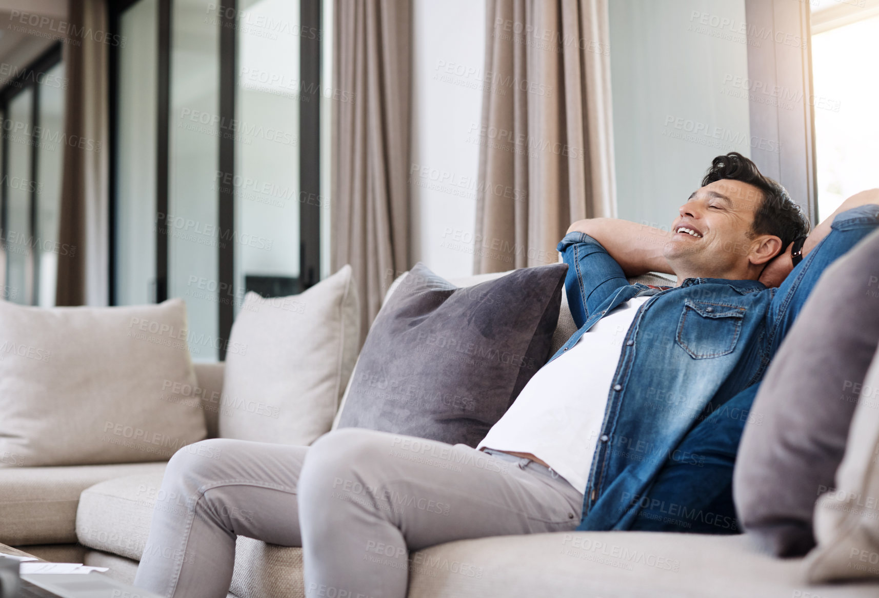 Buy stock photo Shot of a happy young man relaxing on the sofa at home