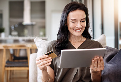 Buy stock photo Shot of an attractive young woman using a digital tablet and credit card at home