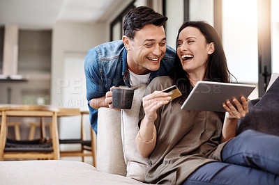 Buy stock photo Shot of a happy young couple using a digital tablet and credit card together at home