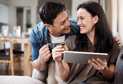 Buy stock photo Shot of a happy young couple using a digital tablet and credit card together at home