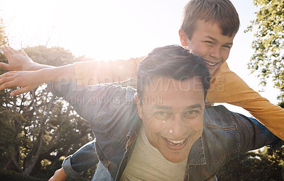 Buy stock photo Shot of a happy father and son enjoying a piggyback ride outdoors