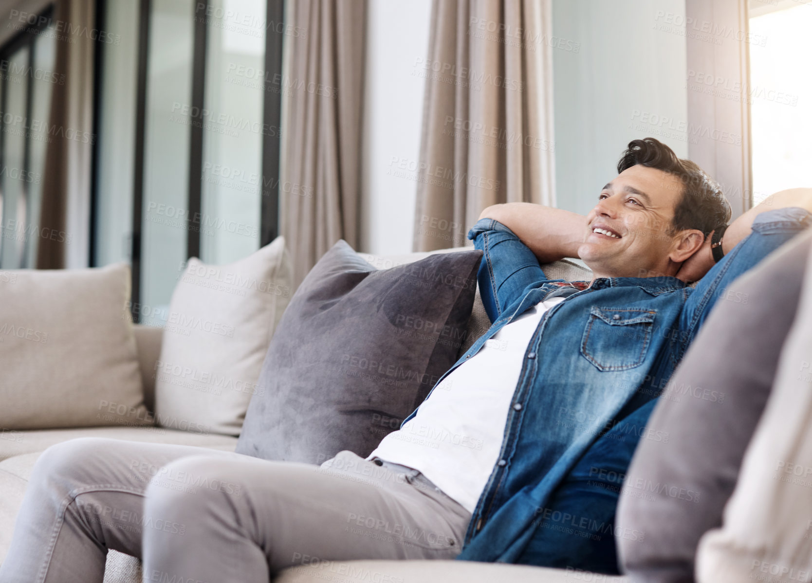 Buy stock photo Shot of a happy young man relaxing on the sofa at home