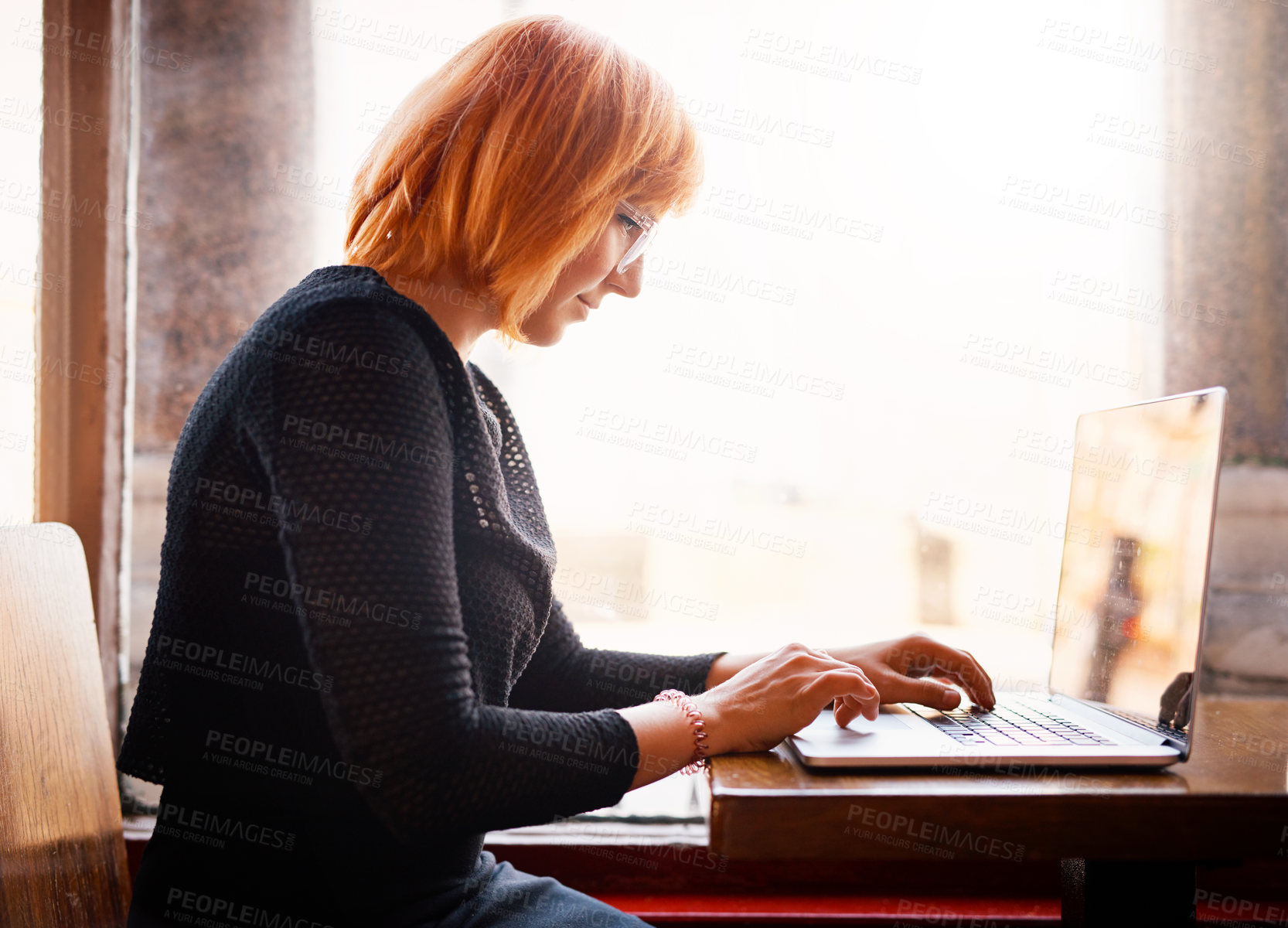 Buy stock photo Cropped shot of a young woman using her laptop in a cafe