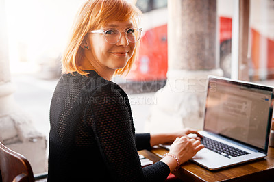 Buy stock photo Cropped shot of a young woman using her laptop in a cafe
