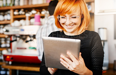 Buy stock photo Shot of a young woman using a digital tablet while working in a coffee shop
