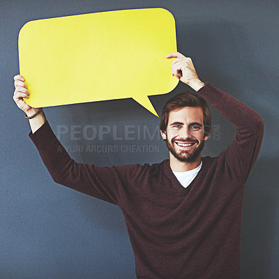 Buy stock photo Studio portrait of a young man holding a speech bubble against a grey background