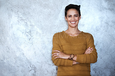 Buy stock photo Portrait of a confident young businesswoman standing with her arms folded against a grey wall