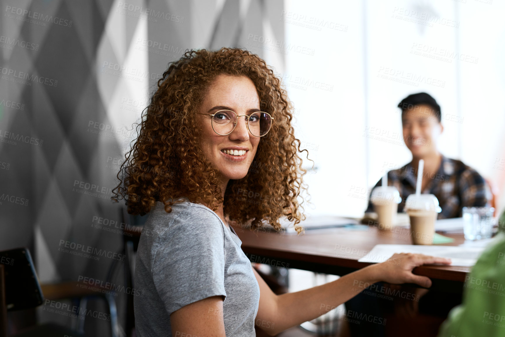 Buy stock photo Cropped portrait of a young designer sitting in an office with her colleagues in the background