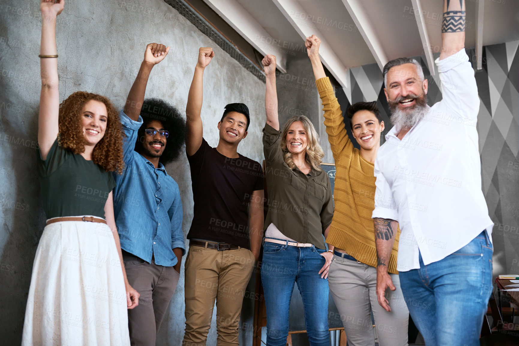 Buy stock photo Cropped portrait of a group of designers raising their fists in unity in a creative office