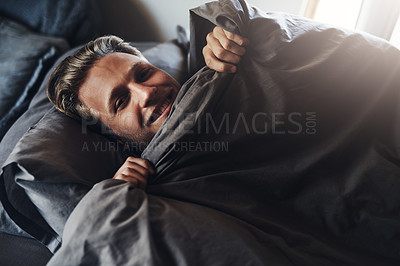 Buy stock photo Shot of a handsome young man relaxing in bed at home