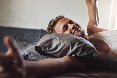 Buy stock photo Shot of a handsome young man waking up in the morning in his bed at home
