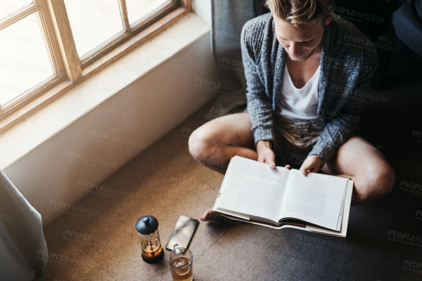 Buy stock photo Man, book and reading on floor for knowledge, entertainment or story in living room. Morning, high angle and person with cup of tea for information, relaxing hobby or studying literature in home