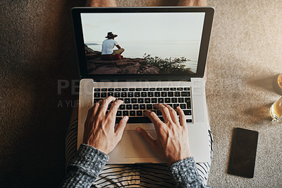 Buy stock photo High angle shot of an unrecognizable man using his laptop while sitting on the floor at home at home