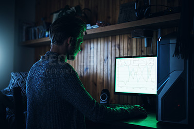 Buy stock photo Shot of a young man using a computer and hacking in a dark room at home