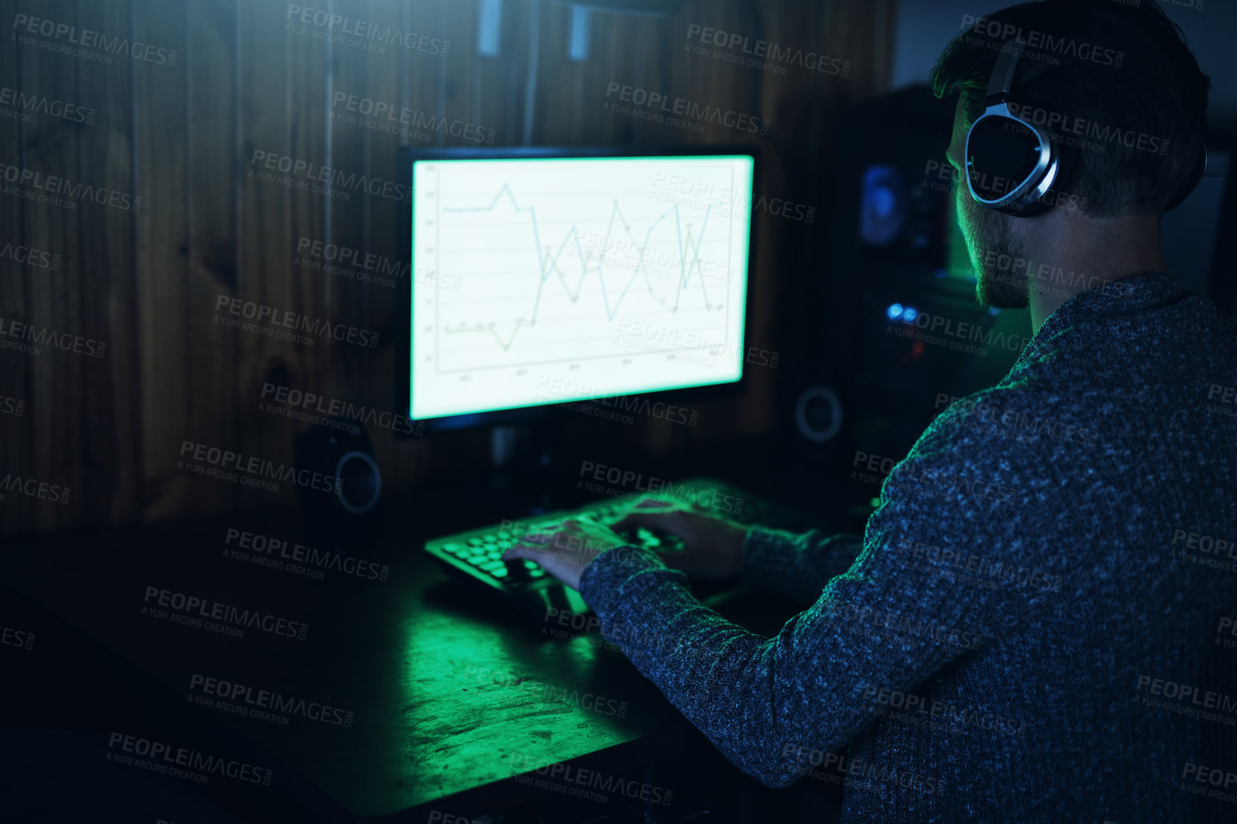Buy stock photo Shot of a young man using a computer and hacking in a dark room at home