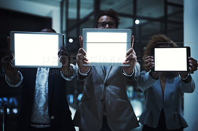 Buy stock photo Cropped shot of a group of unrecognizable businesspeople showing the screens of their tablets while working late in the office