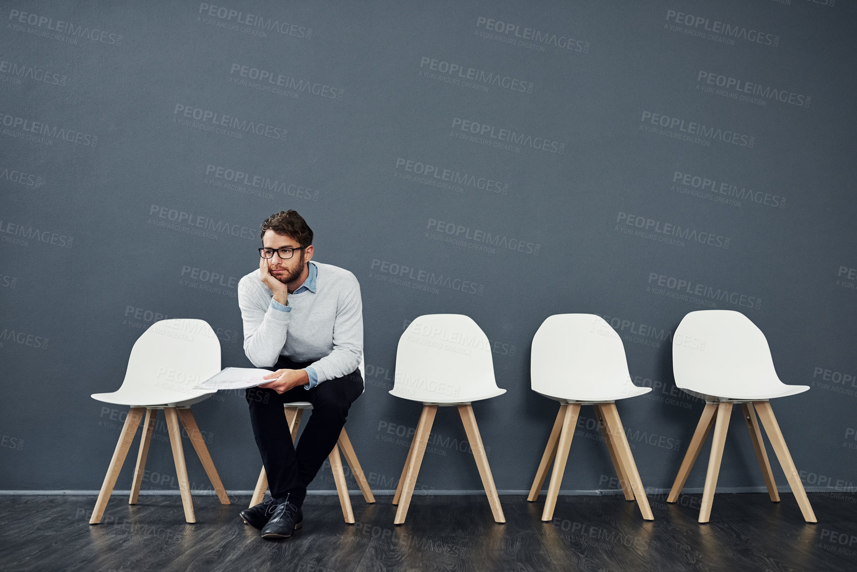 Buy stock photo Cropped shot of a handsome young man looking bored while waiting in line for a job interview