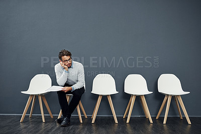 Buy stock photo Cropped shot of a handsome young man looking bored while waiting in line for a job interview