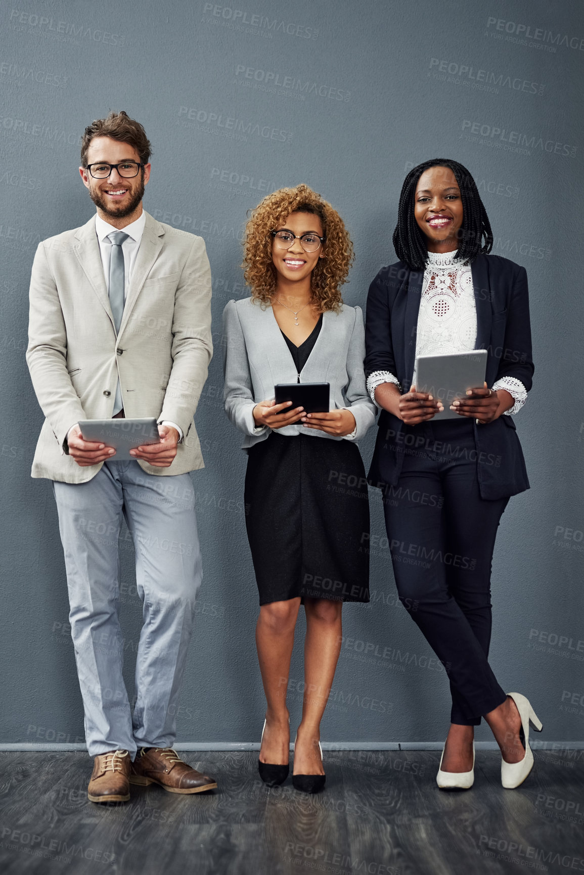 Buy stock photo Full length portrait of a group of businesspeople using digital tablets against a grey background