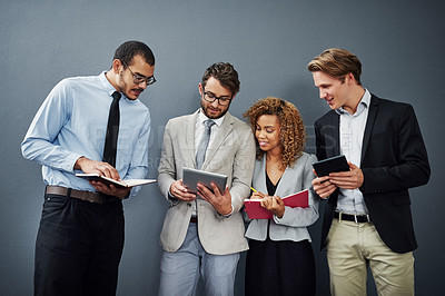 Buy stock photo Cropped shot of a group of businesspeople using digital tablets and notebooks while waiting in line for a job interview
