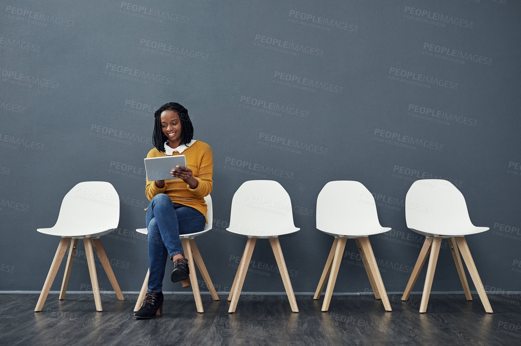 Buy stock photo Business woman, tablet and waiting room of interview, recruitment or human resources website for sign up. African worker reading of opportunity, news or digital job search on chair by wall background