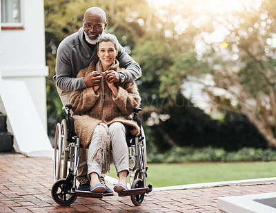 Buy stock photo Shot of an elderly man pushing his wheelchair-bound wife around the yard at home