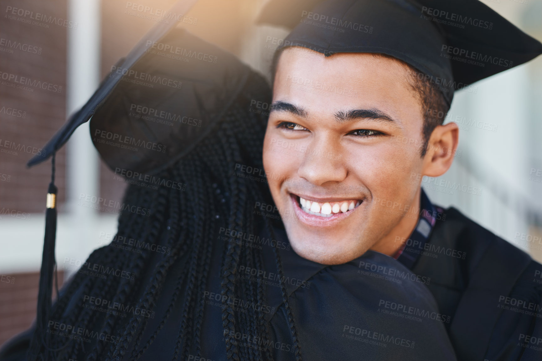 Buy stock photo Shot of two happy young students hugging each other on graduation day