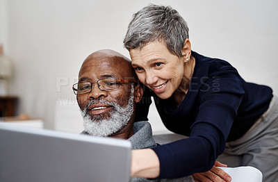 Buy stock photo Shot of an affectionate senior couple using a laptop together while relaxing on the sofa at home