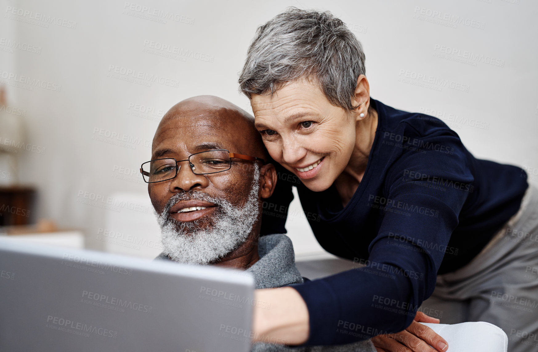 Buy stock photo Shot of an affectionate senior couple using a laptop together while relaxing on the sofa at home