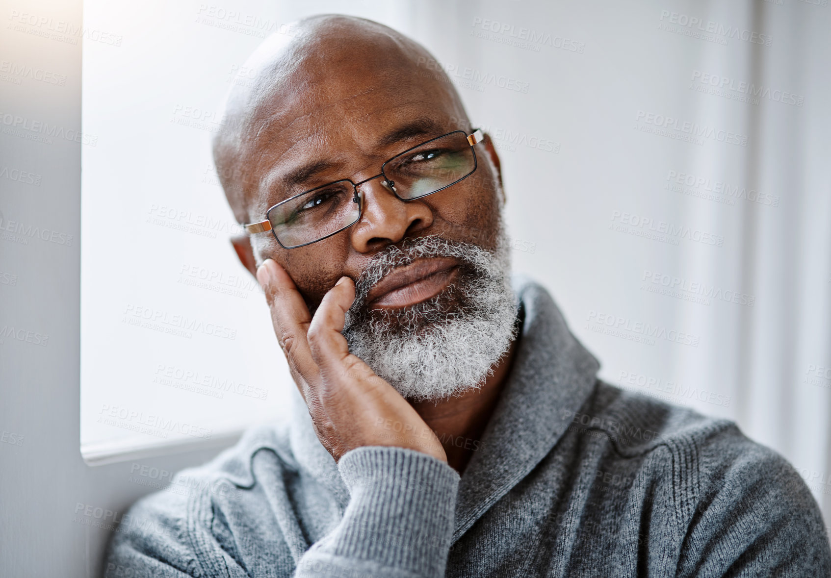 Buy stock photo Shot of a handsome senior man looking thoughtful while sitting in his home