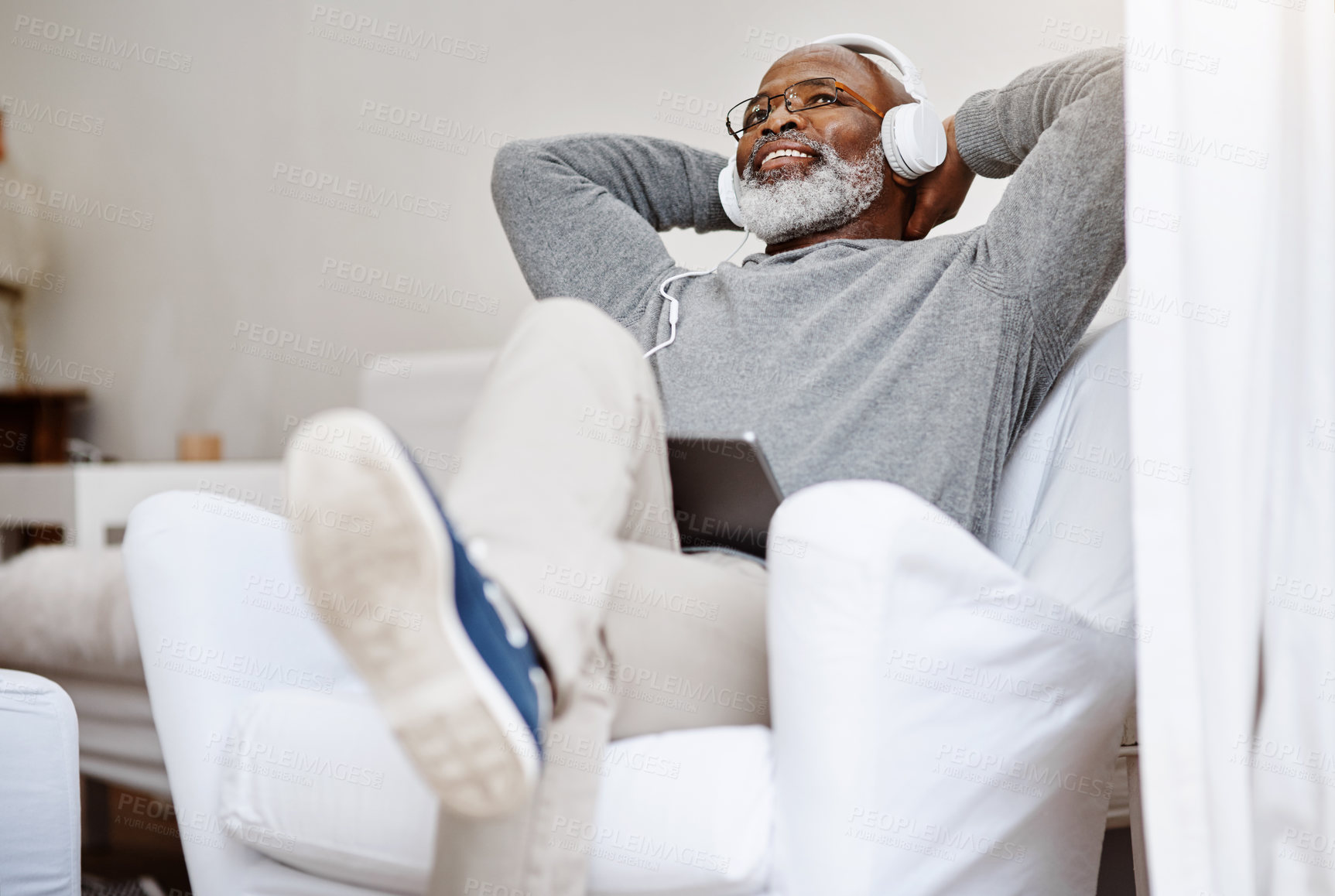 Buy stock photo Senior black man, relax and streaming music, podcast or jazz on radio in living room. Headphones, retirement and happy person listening to sound, audio therapy or playlist on tablet in home on sofa