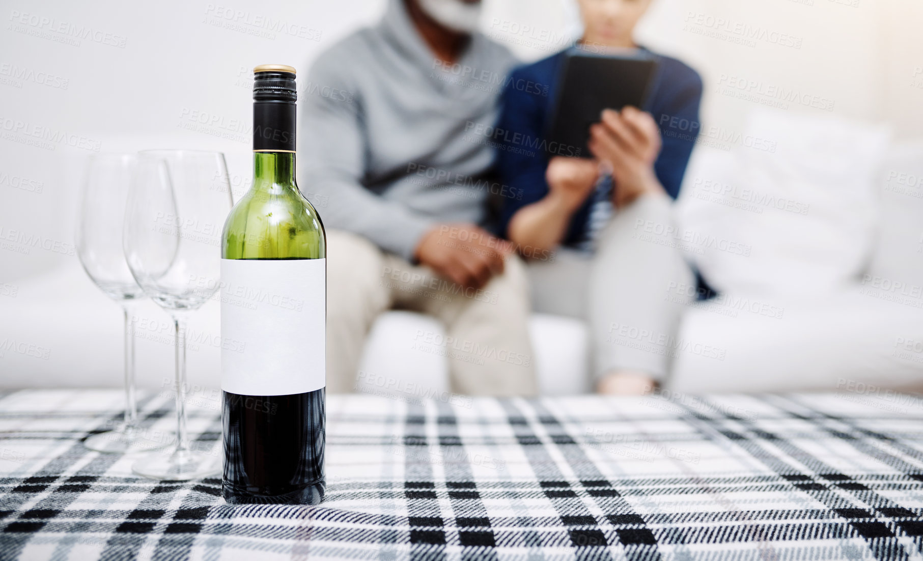 Buy stock photo Shot of an unrecognizable senior couple relaxing on a sofa with their bottle of wine and glasses waiting on a table at home