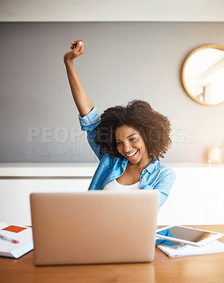Buy stock photo Shot of an attractive young woman cheering with her arm raised while working on her laptop at home